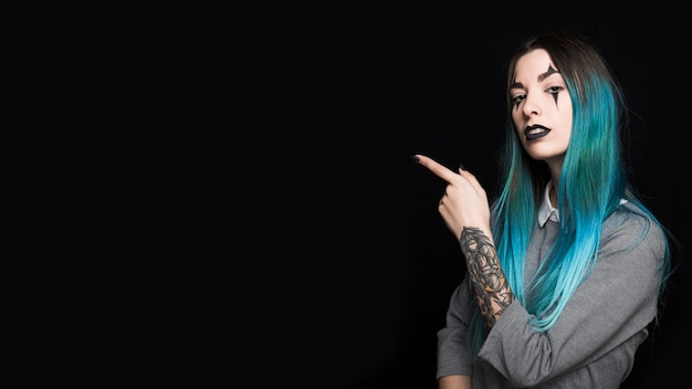 Jovem mulher com cabelo azul, apontando com o dedo de lado Foto gratuita