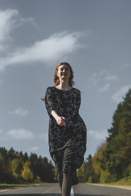 Jovem mulher com longos cabelos ruivos em um vestido de linho em um local natural no fundo Foto gratuita