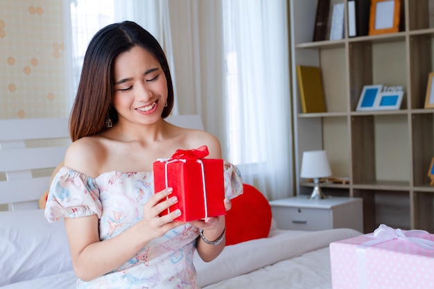 Jovem mulher feliz com presente vermelho no quarto Foto gratuita