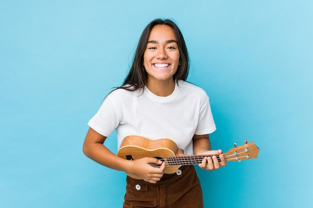 Jovem mulher indiana tocando ukelele feliz Foto Premium