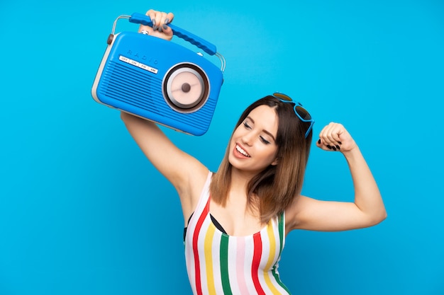 Jovem mulher nas férias de verão na parede azul, segurando um rádio Foto Premium