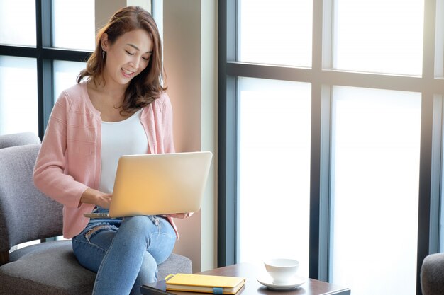 Jovem mulher negócios on-line usando laptop com sorvendo café em um clima confortável. Foto Premium