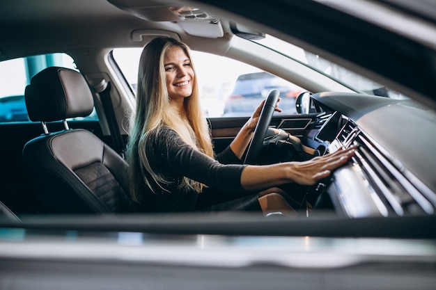 Jovem mulher testando um carro em uma sala de exposições | Foto Grátis