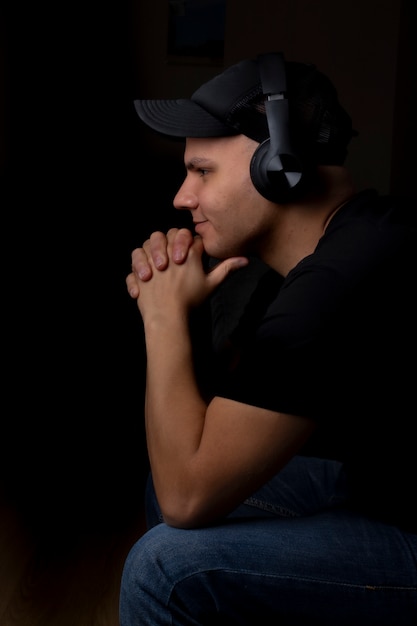 Jovem ouvindo música com seus fones de ouvido no escuro Foto Premium