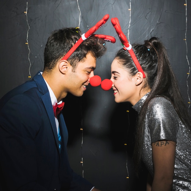Jovem, par feliz, com, veado vermelho, antlers headbands, e, engraçado, narizes Foto gratuita