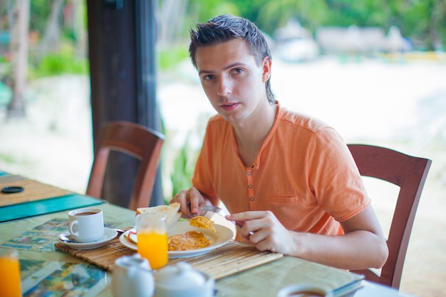 Jovem tomando café da manhã no restaurante do resort Foto Premium