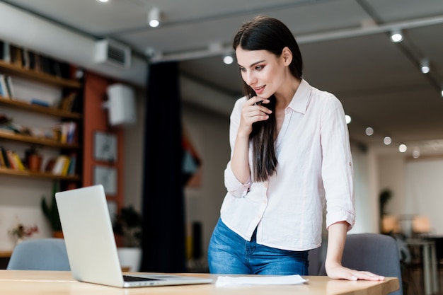 Jovem trabalha no escritório com laptop Foto Premium
