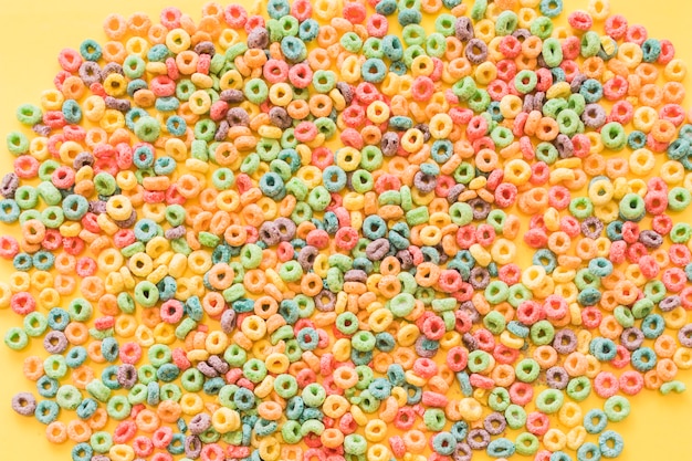 Laço de cereal colorido anéis no pano de fundo amarelo Foto gratuita