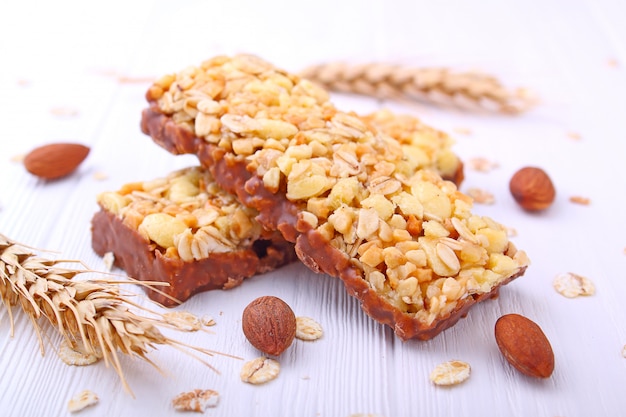 Lanche saudável, barras de muesli com passas e nozes em um fundo branco Foto Premium