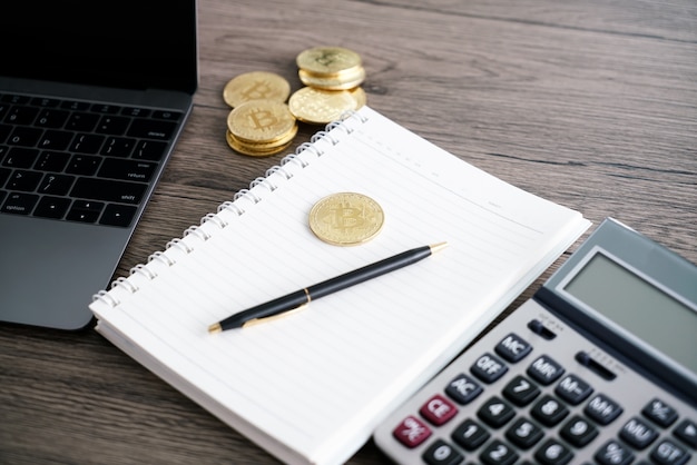 Laptop com calculadora e bitcoin dourado. conceito de investidores de criptomoeda. Foto Premium