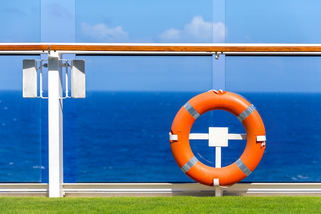 Lifebuoy laranja em um convés de navio de cruzeiro com o oceano no fundo com espaço de céu azul e cópia Foto Premium