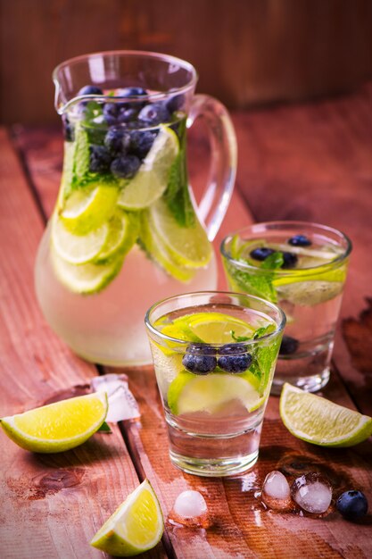 Limonada com limão fresco, frutas e hortelã no fundo de madeira Foto Premium