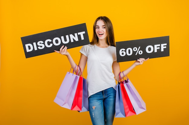 Linda mulher morena com sacolas coloridas e copyspace texto disconto banner de sinal de 60% isolado sobre o amarelo Foto Premium