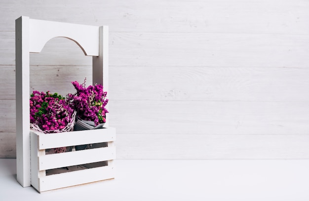 Lindas flores roxas minúsculas em caixas na mesa contra o pano de fundo de madeira Foto gratuita