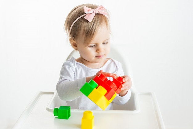 Lindo Bebe Loiro Brinca Com Um Construtor Brilhante Sobre Uma Mesa Branca Criatividade Infantil Em Quarentena Desenvolvimento Precoce De Criancas Foto Premium