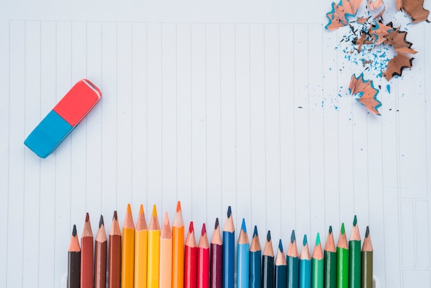 Linha de cores de lápis com borracha e lápis de barbear em papel branco Foto gratuita