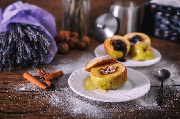 Maçã assada recheada com nozes, mel e chocolate em pratos de sobremesa branco, fundo escuro de madeira. doce de natal. conceito de alimentação saudável. Foto Premium