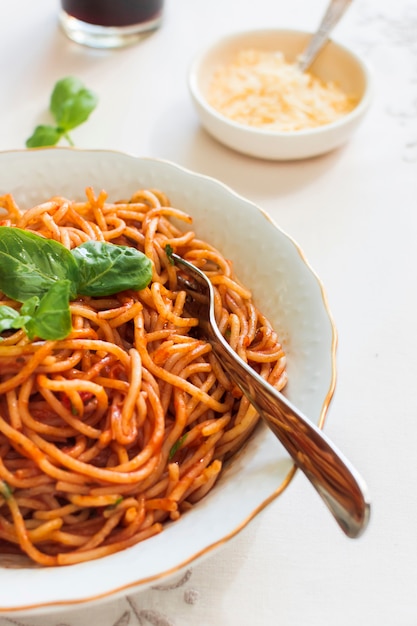 Macarrão com molho de tomate e manjericão na placa cerâmica com garfo Foto gratuita