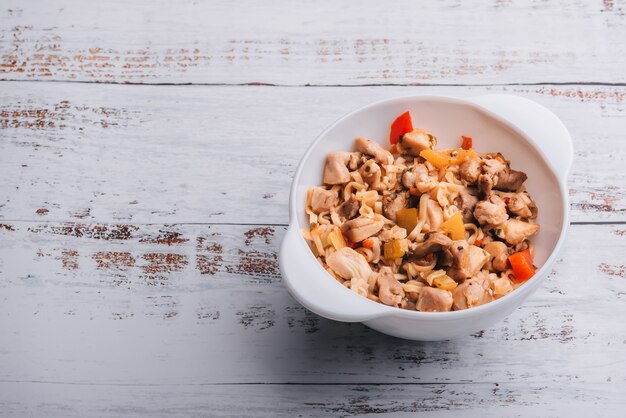 Macarrão instantâneo com frango e pimenta com molho picante em uma tigela branca Foto Premium