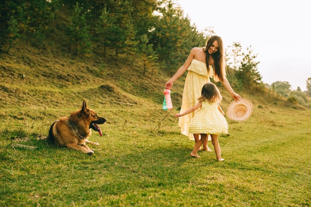 Mãe anda com sua filhinha e seu cachorro Foto Premium