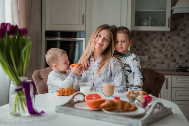 Mãe com filhos tomando café na cozinha Foto Premium