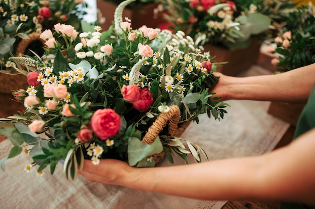 Mão de uma mulher segurando cesta pf flores frescas Foto gratuita
