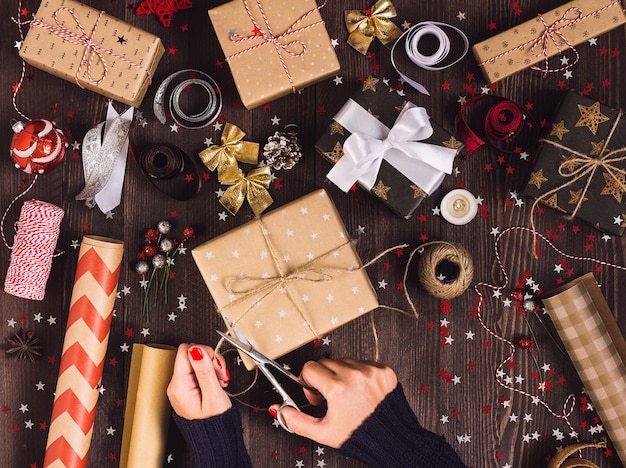 Mão mulher, segurando, corda guita, com, tesouras, para, corte, e, empacotando, caixa presente natal Foto gratuita