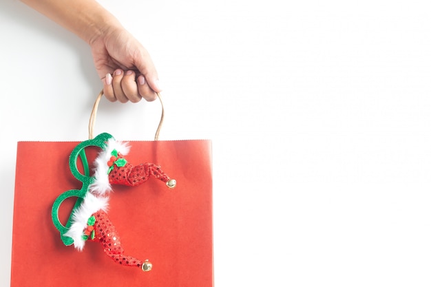 Mão segurando o saco de compras de natal em fundo branco Foto Premium