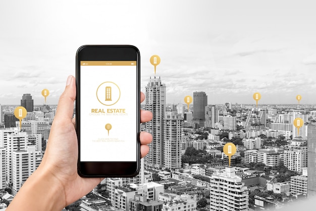 Mão segurando o smartphone com o aplicativo para encontrar imóveis na tela Foto Premium
