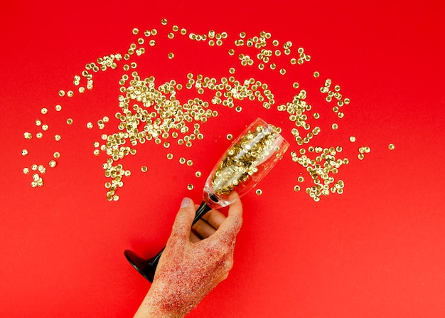 Mão segurando o vidro com glitter dourado Foto gratuita