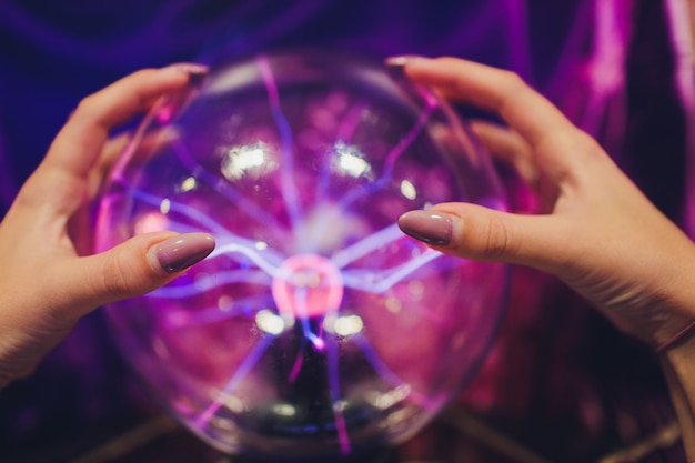 Mão tocando uma bola de plasma com suaves chamas azul-magenta. Foto Premium