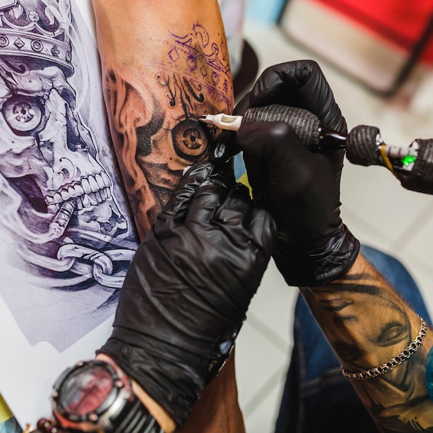 Mãos fazendo tatuagem na mesa com desenho | Foto Grátis