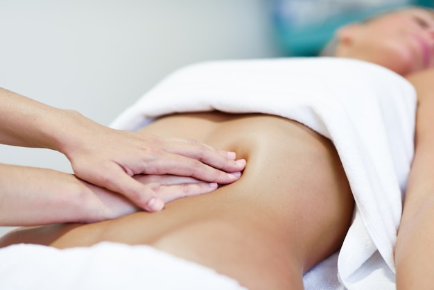 Mãos massageando o abdômen feminino.therapista aplicando pressão sobre a barriga. Foto gratuita