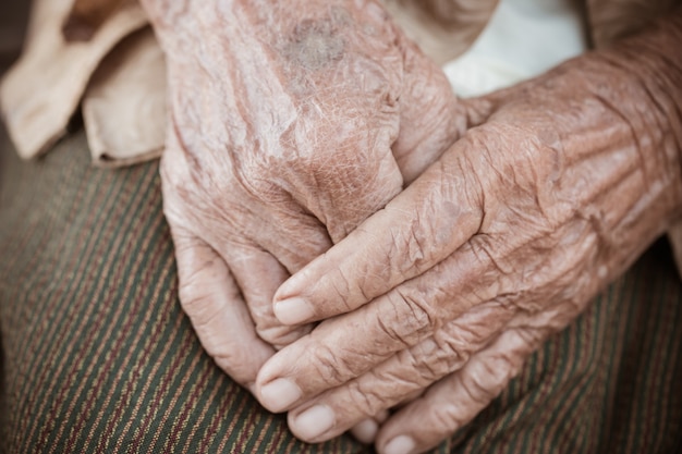 Mãos mulher idosa asiática agarra sua mão no colo | Foto Premium