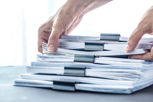 Mãos, tocando o papel de escritório. empilha arquivos de documentos com clipe preto. Foto Premium