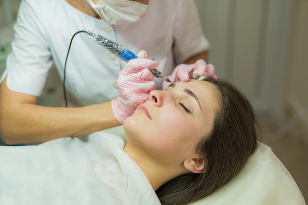 Maquiagem permanente (tatuagem) nas sobrancelhas no salão de beleza mulher com as sobrancelhas tingidas. maquiagem semi-permanente para sobrancelhas. Foto Premium