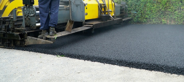 Máquina pavimentadora de asfalto durante obras de reparação rodoviária Foto Premium