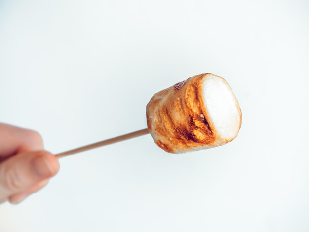 Marshmallows assados no espeto em mão feminina em branco Foto Premium