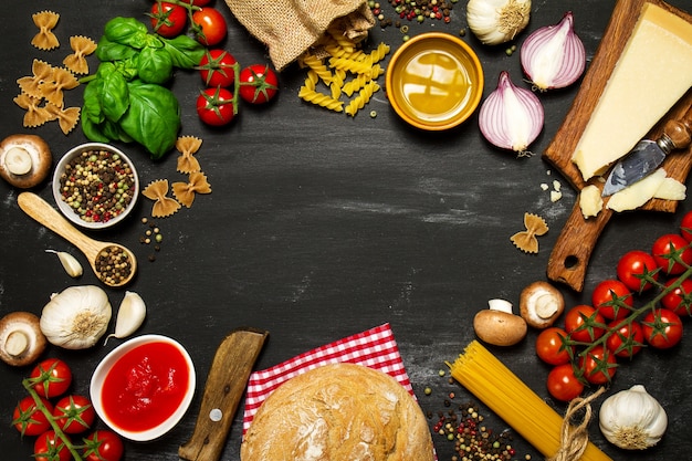 Massa crua com tomates e queijo em uma tabela preta que fazem um círculo Foto Premium Massa crua com tomates e queijo em uma tabela preta que fazem um círculo Foto Premium