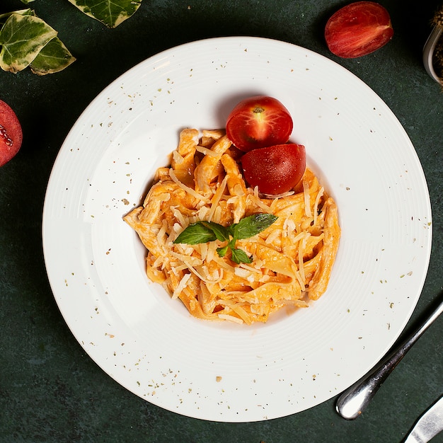 Massa no molho de tomate com parmesão, tomate e basilic desbastados. Foto gratuita
