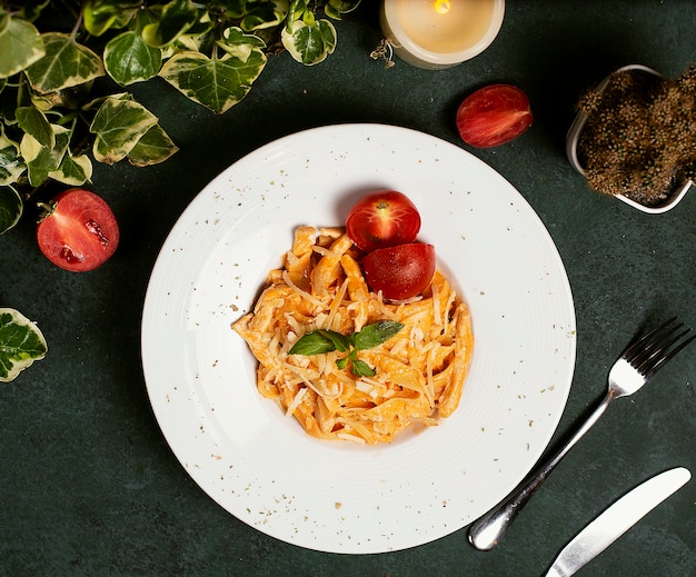 Massa no molho de tomate com parmesão, tomate e basilic desbastados. Foto gratuita