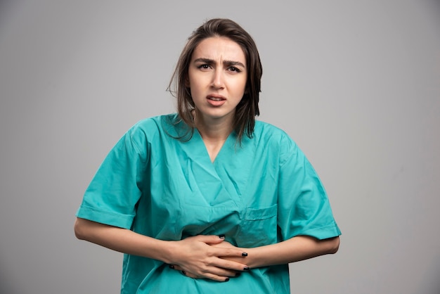 Medica Com Dor De Estomago Em Fundo Cinza Foto De Alta Qualidade Foto Gratis