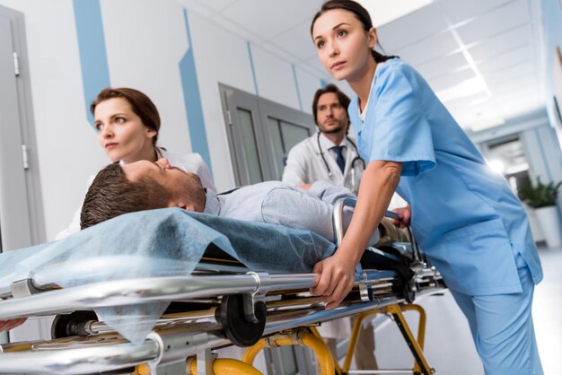 Médicos e enfermeira transportando paciente inconsciente na maca | Foto ...