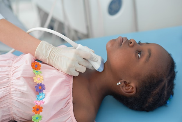 Menina afro, deitada na cama enquanto ultra-som da tireóide. Foto Premium