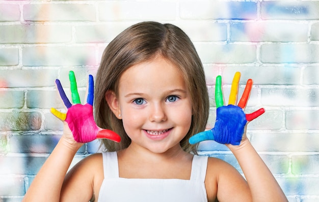 Menina bonitinha as mãos pintadas de cores no fundo Foto Premium