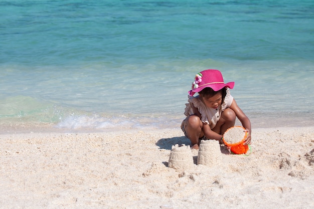 Criança bonito brincar com areia na praia. Miúdo a brincar 