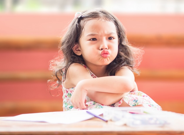 Menina bonito pequena irritada com cruz seu braço quando sua mãe proíbe a observação de desenhos animados e diz-lhe para tirar. Foto Premium