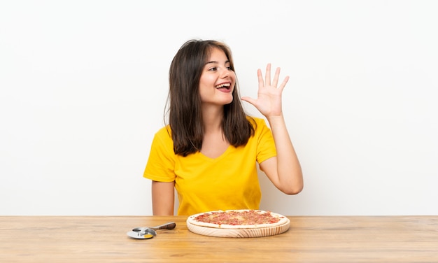 Menina branca com uma pizza gritando com a boca aberta Foto Premium
