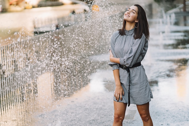 Menina brincando e dançando em uma rua molhada Foto gratuita