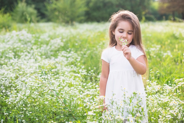 menina-cute-cheirando-a-flor-no-campo_23